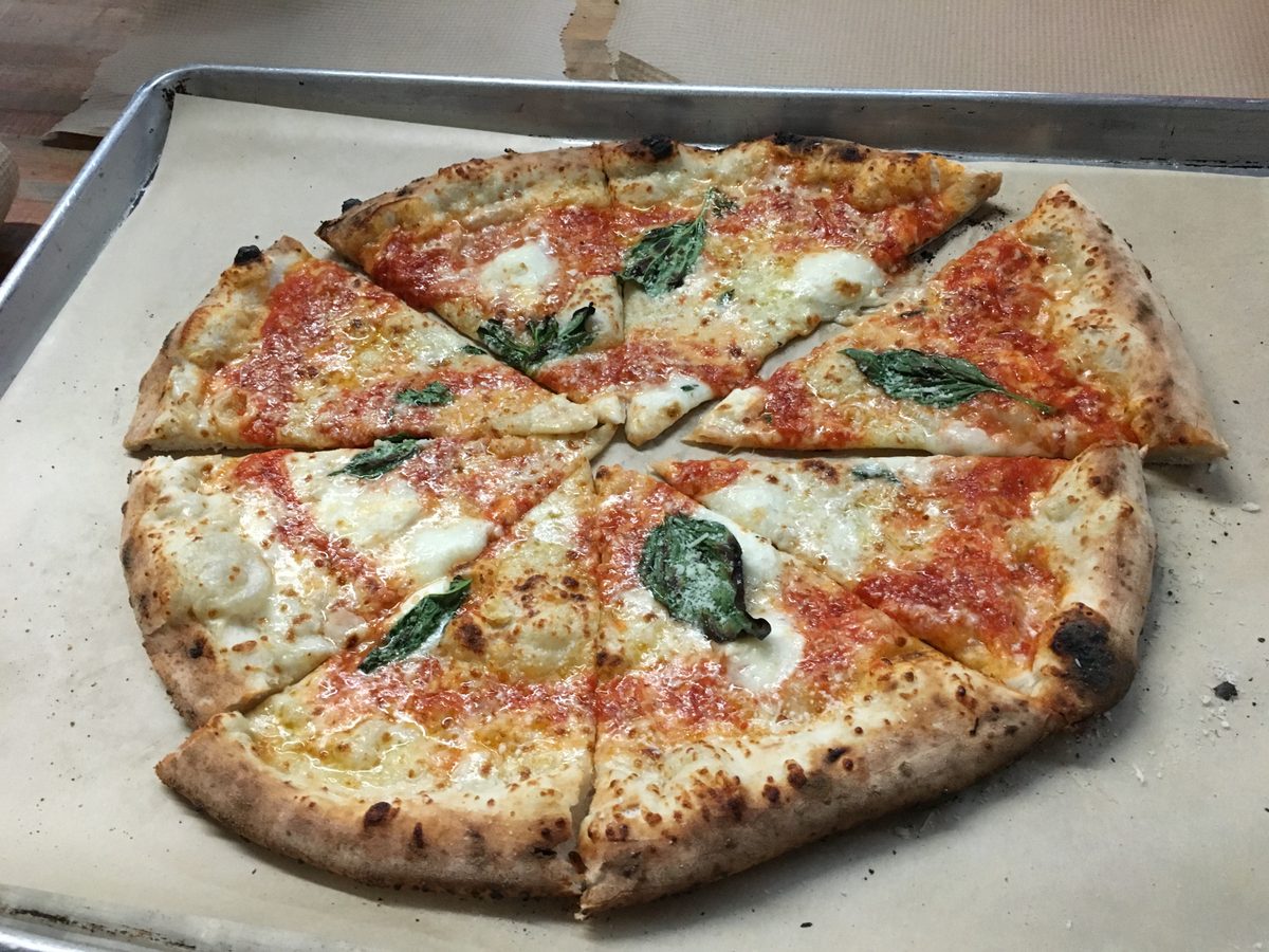 cheese pie sliced into wedges with sausage bits and basil, Antico Pizza
