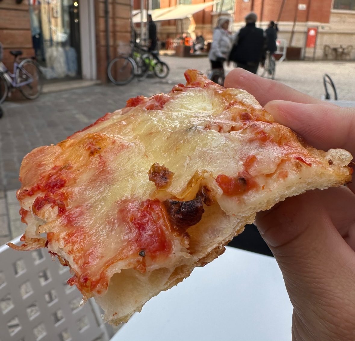 hand holding a folded cheesy square slice, Bella Mia