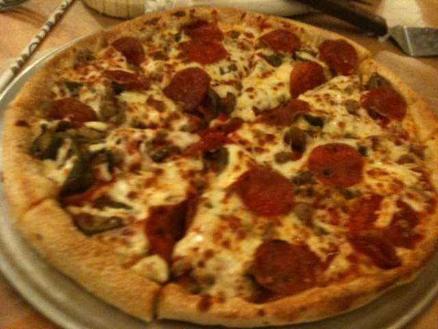 Blurry photo of a loaded pie with pepperoni and peppers, Pizza Tower