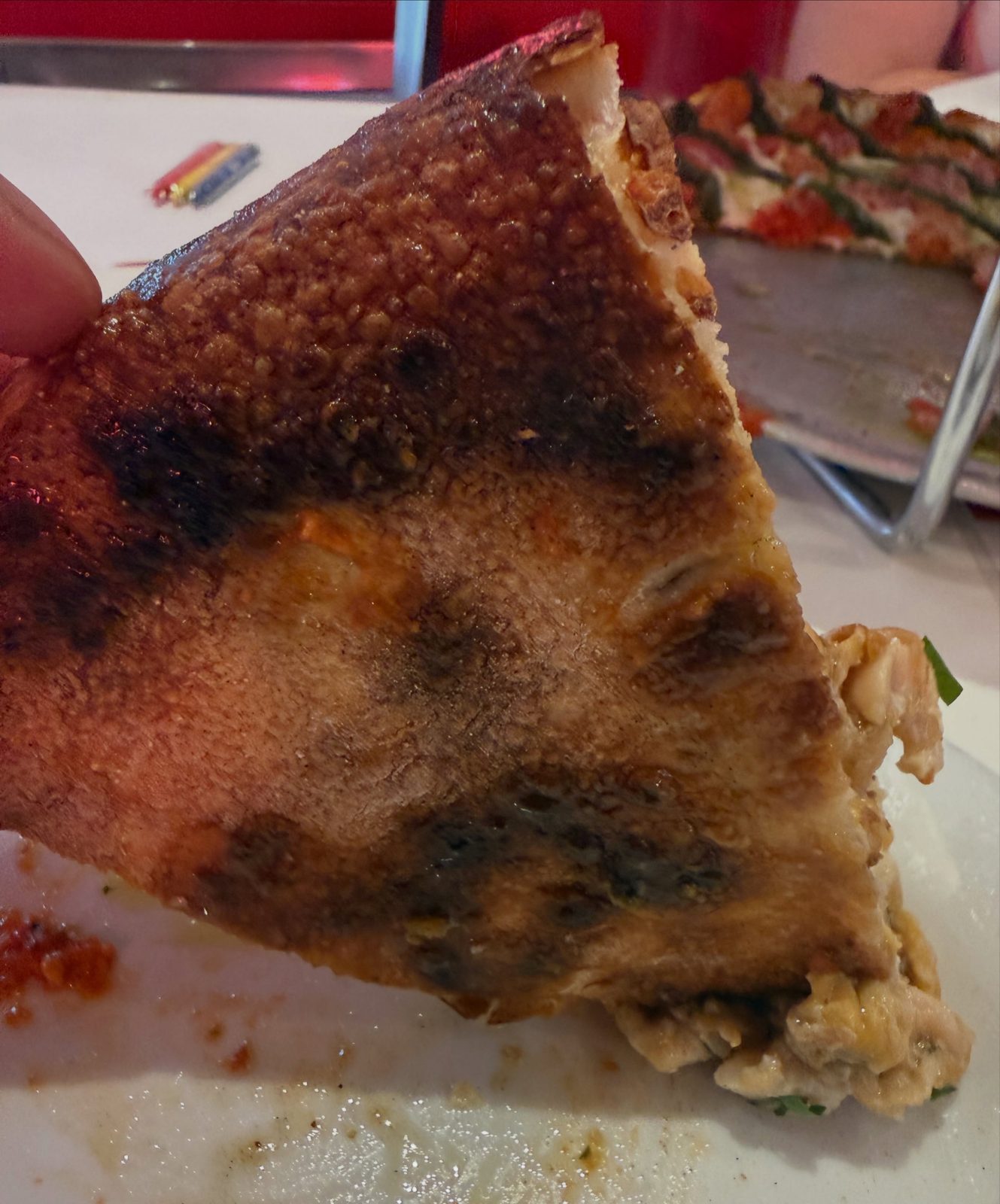 Underside of a clam pie slice at Andrew Bellucci’s Pizzeria, blistered and browned