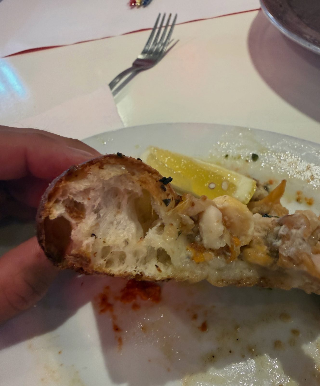 Cut edge of the clam pie showing an airy, open crumb under clams and herbs