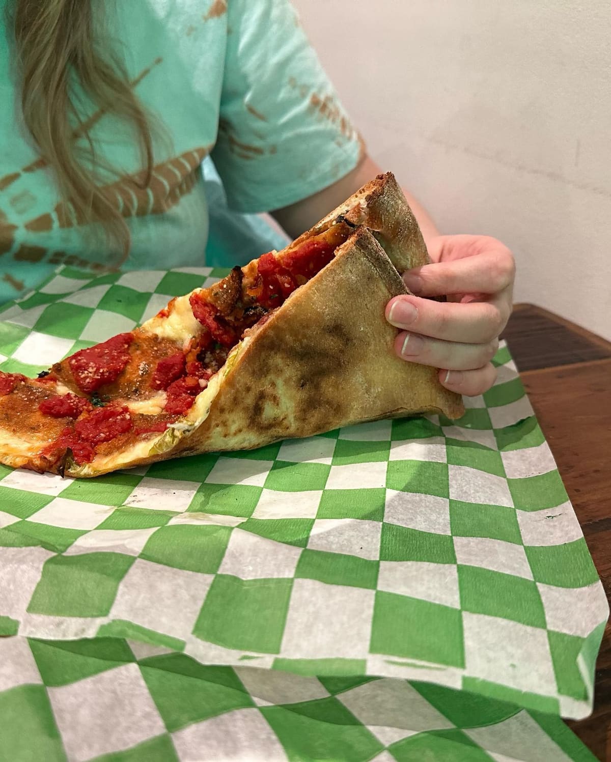 Pizza slice held up for a closer view at Baked by Luigi