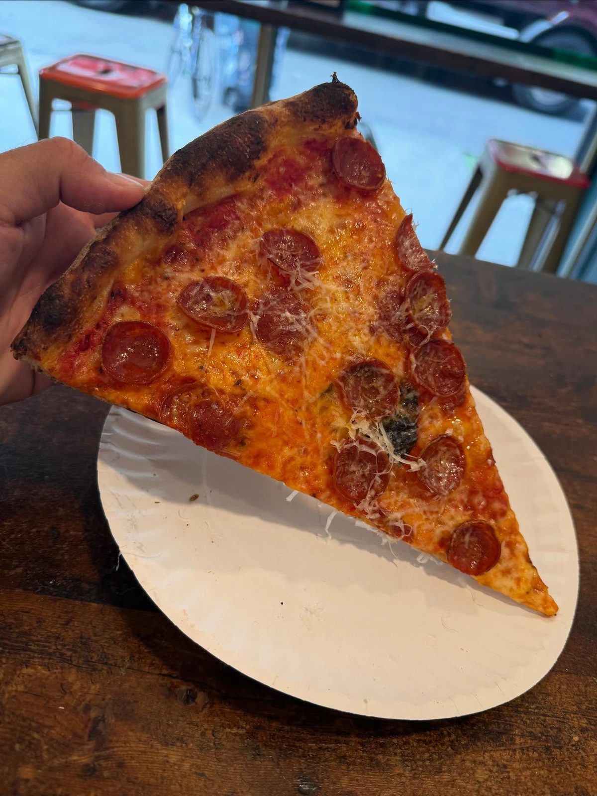 Pizza slice held up for a closer view at Cello’s Pizzeria