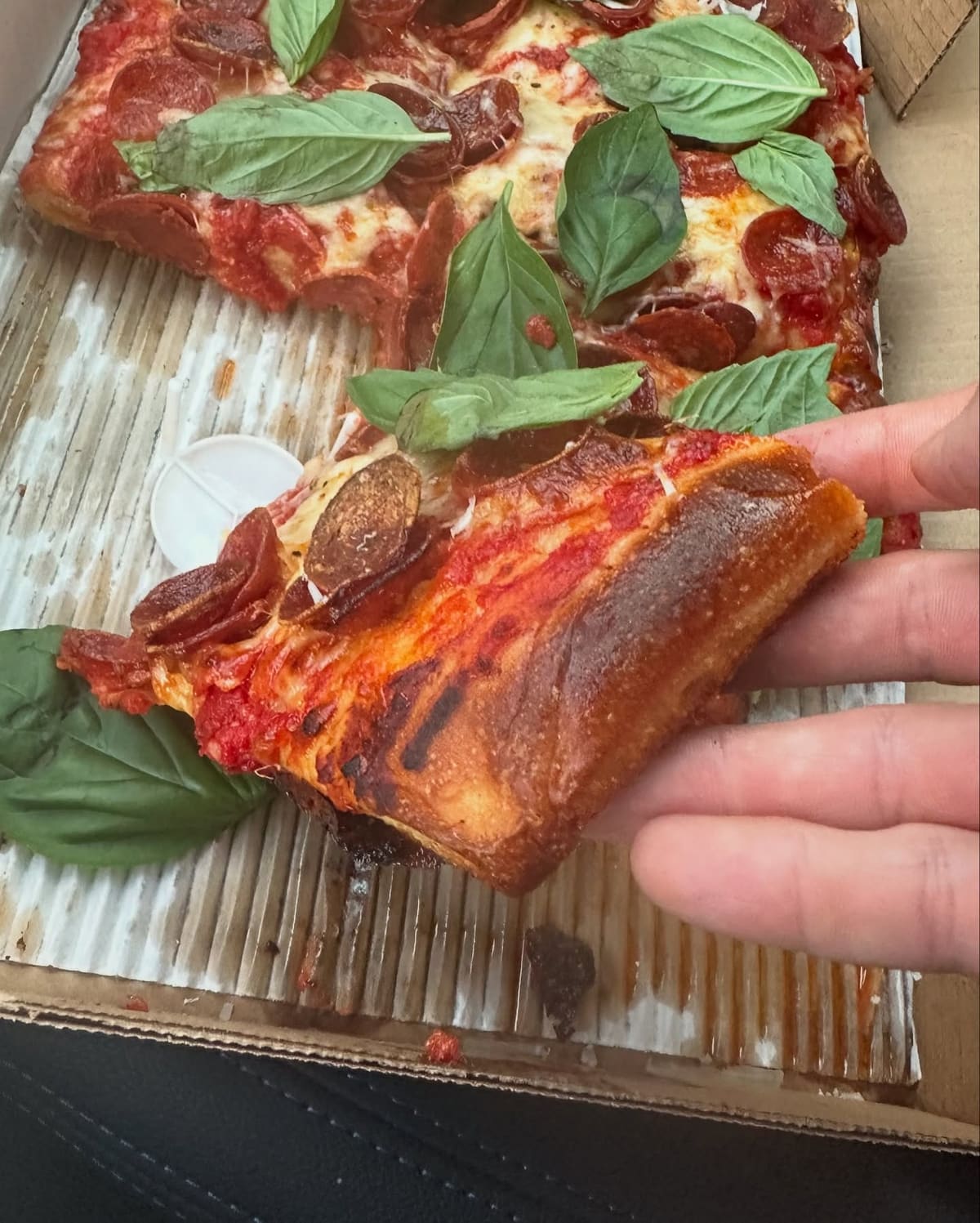 Pizza slice held up for a closer view at Daughter’s Pizza