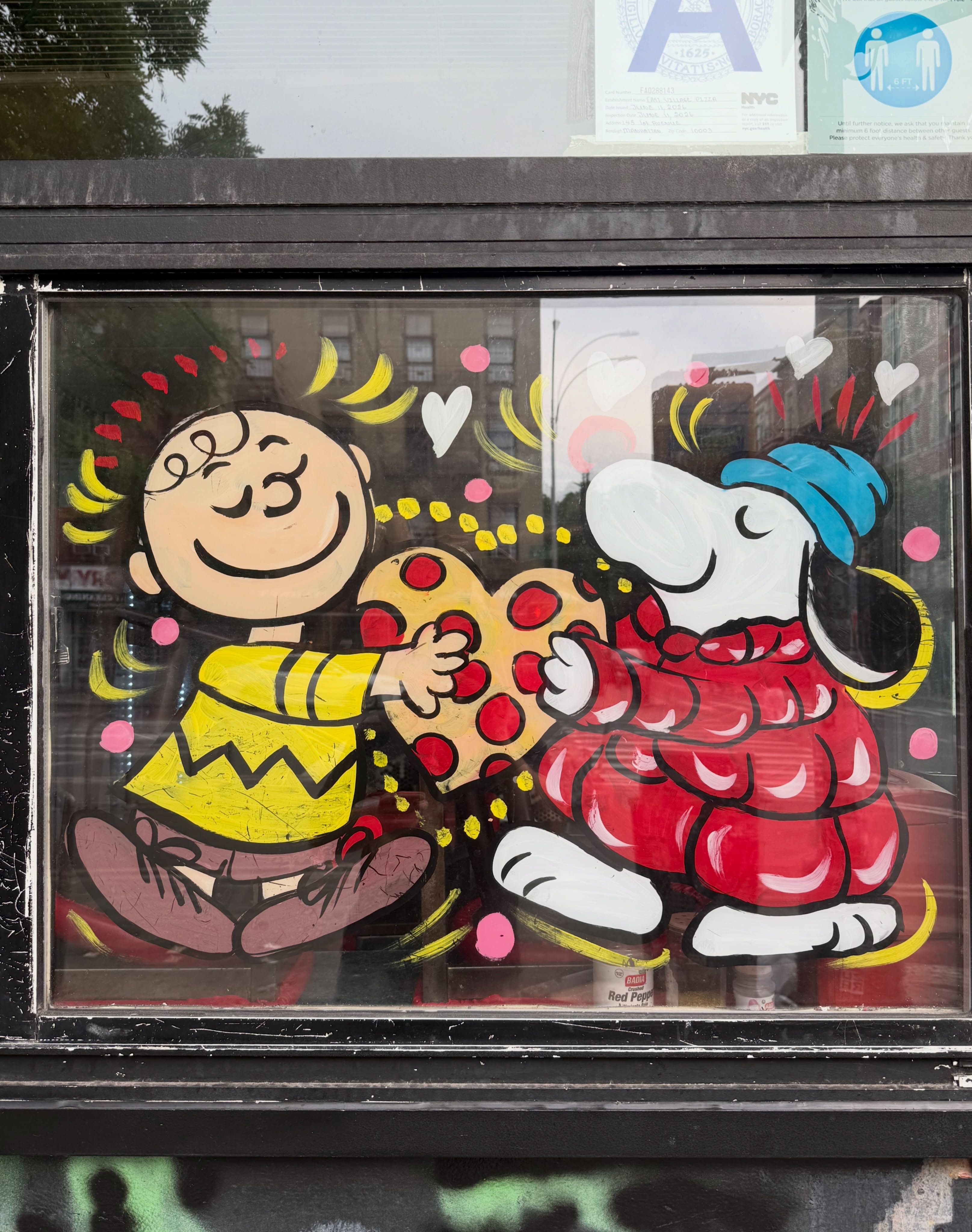 Hand-painted window art of Peanuts characters holding a pizza, East Village Pizza