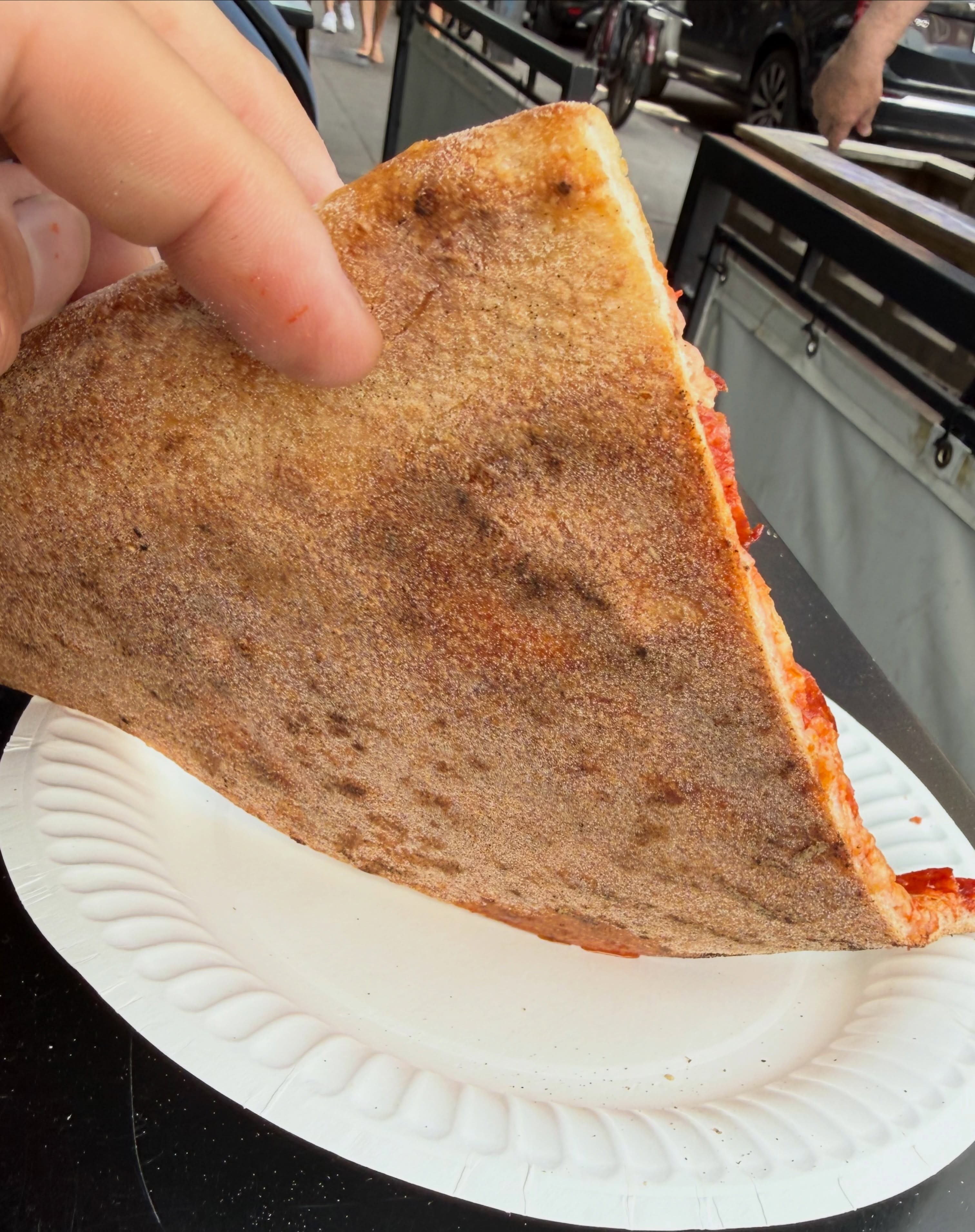 Evenly browned underside of the slice, East Village Pizza