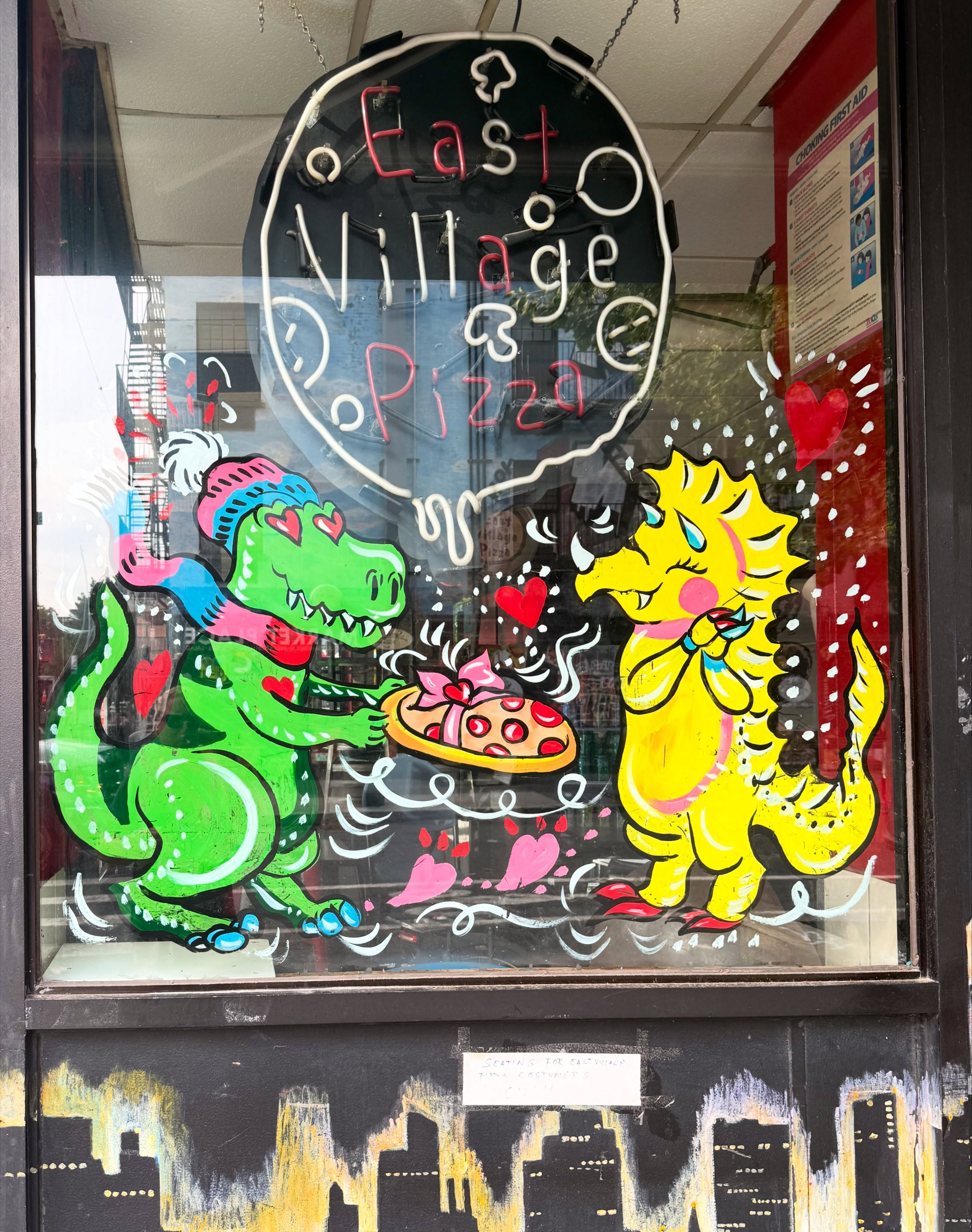 Hand-painted window art of two dinosaurs sharing a pizza, East Village Pizza