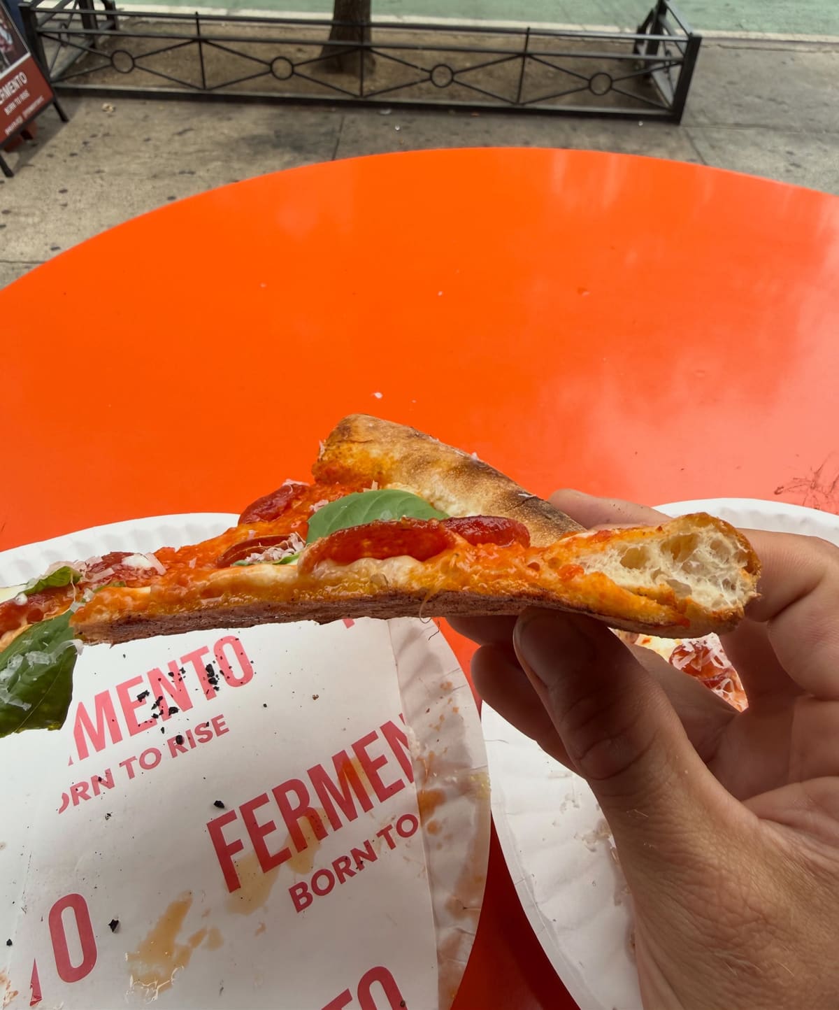 Pizza slice held up for a closer view at Fermento in West Village