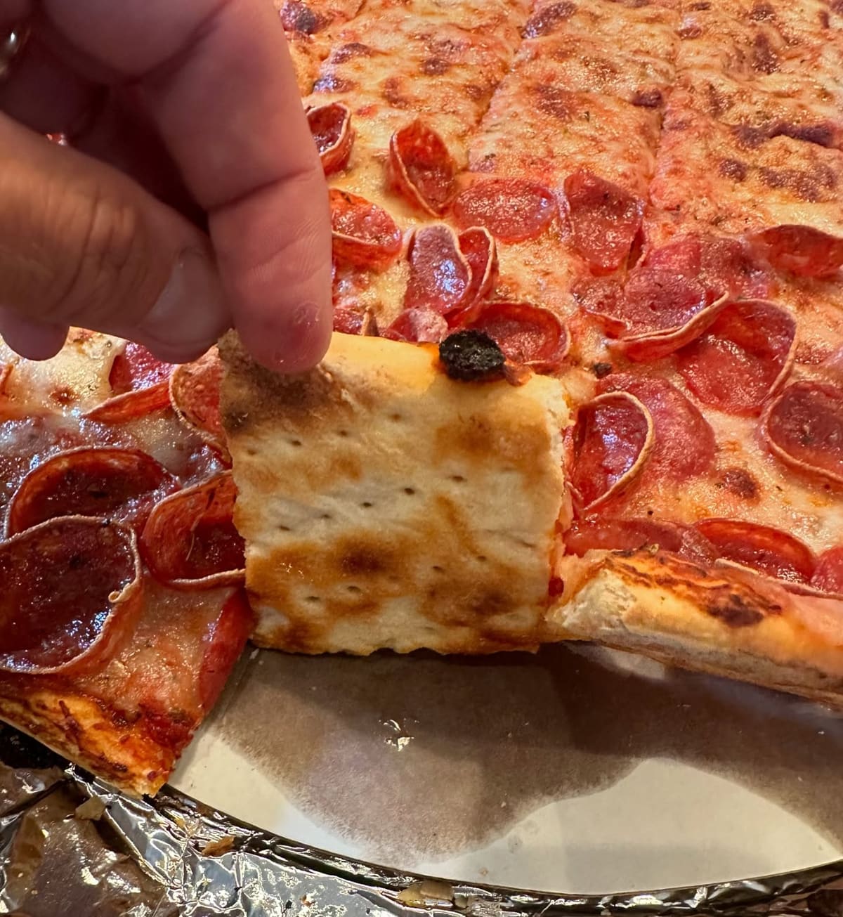 Pizza slice held up for a closer view at Joe’s Pizzeria