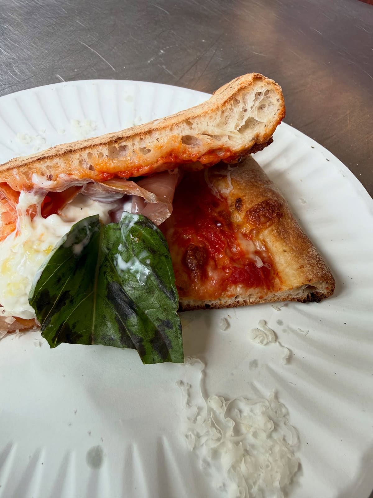 Side profile of a pizza slice at L’Industrie in Little Italy