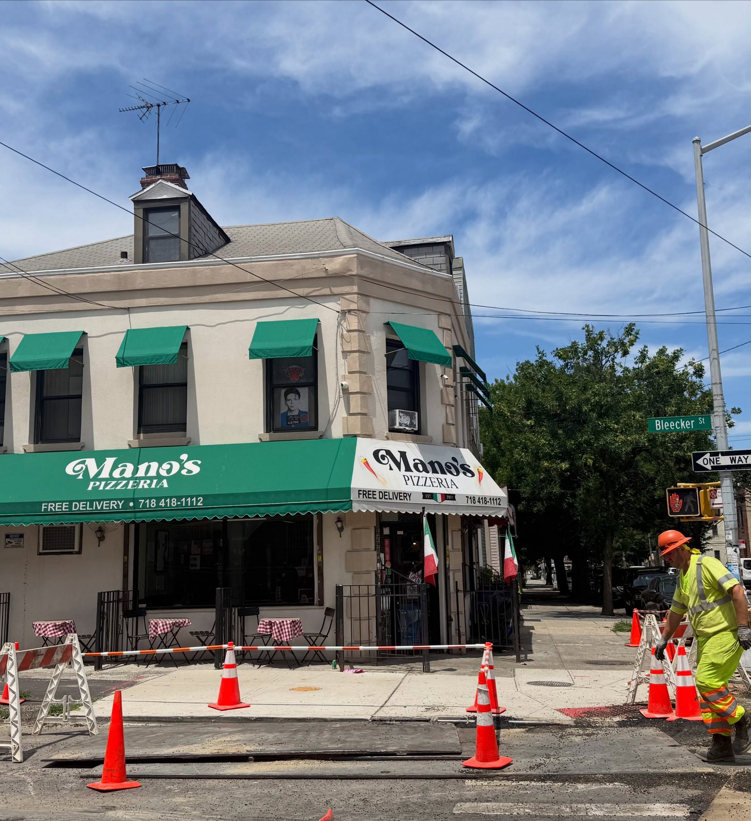 Corner storefront with a green awning at Mano's Pizza in Ridgewood