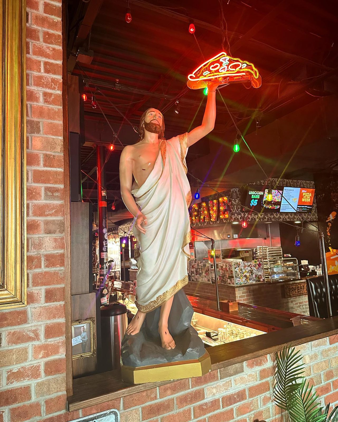 Statue holding a pizza aloft inside Mikey’s Late Night Slice