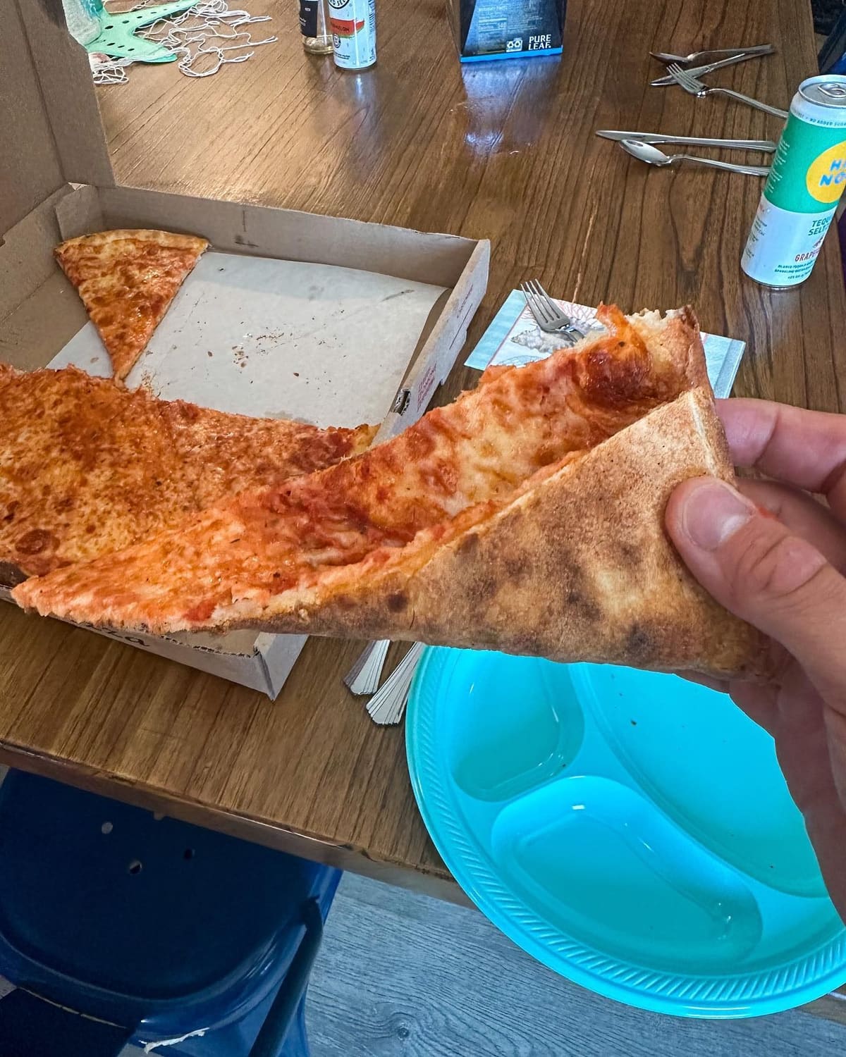 Pizza slice held up for a closer view at Naples Pizza & Restaurant