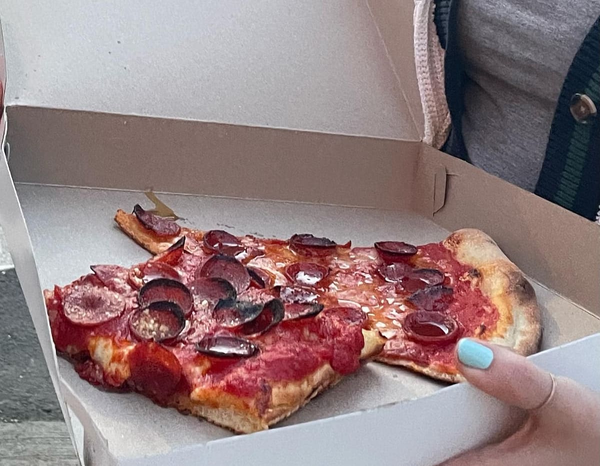 Pizza slice held up for a closer view at Paulie Gee’s Slice Shop
