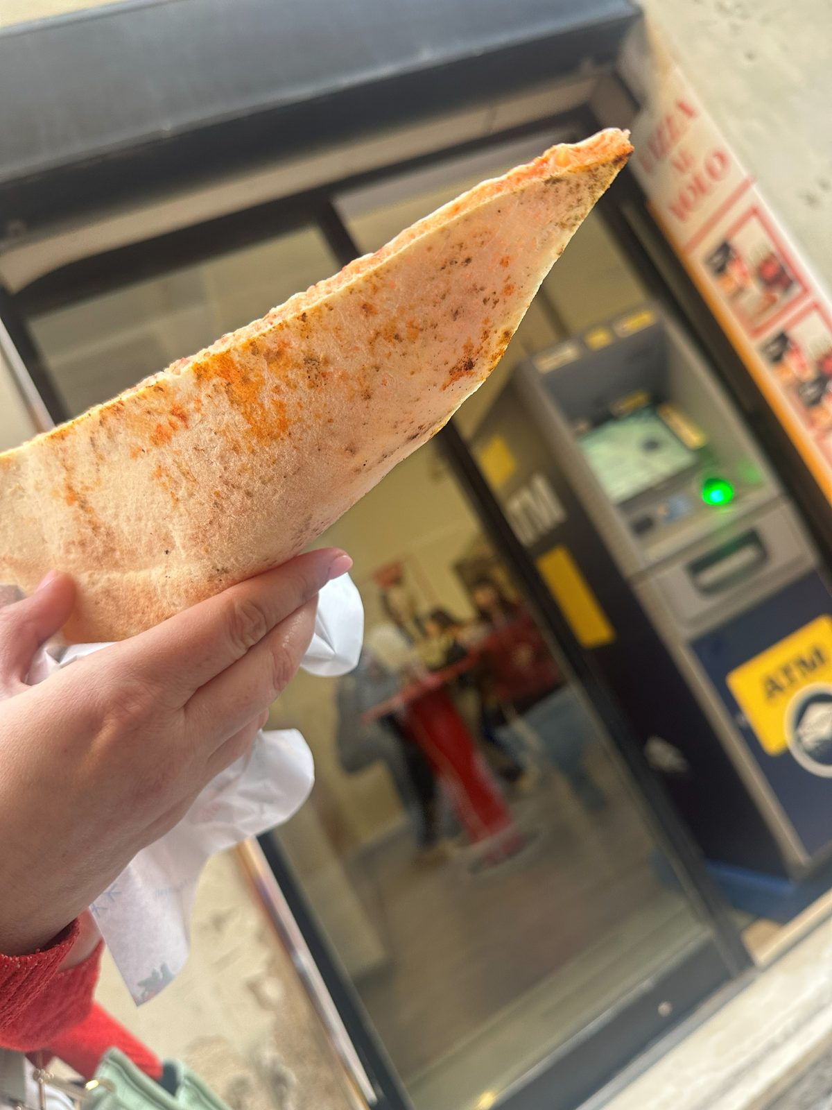 Slice folded in paper, held on a Siena street, Pizza Al Volo