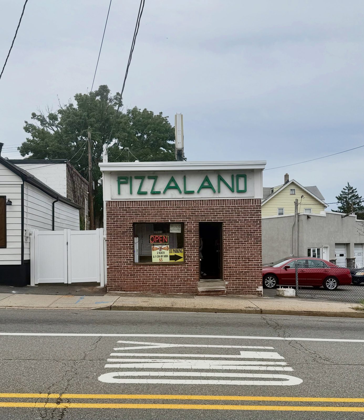 The small brick storefront of Pizzaland in North Arlington, green letters across a white parapet