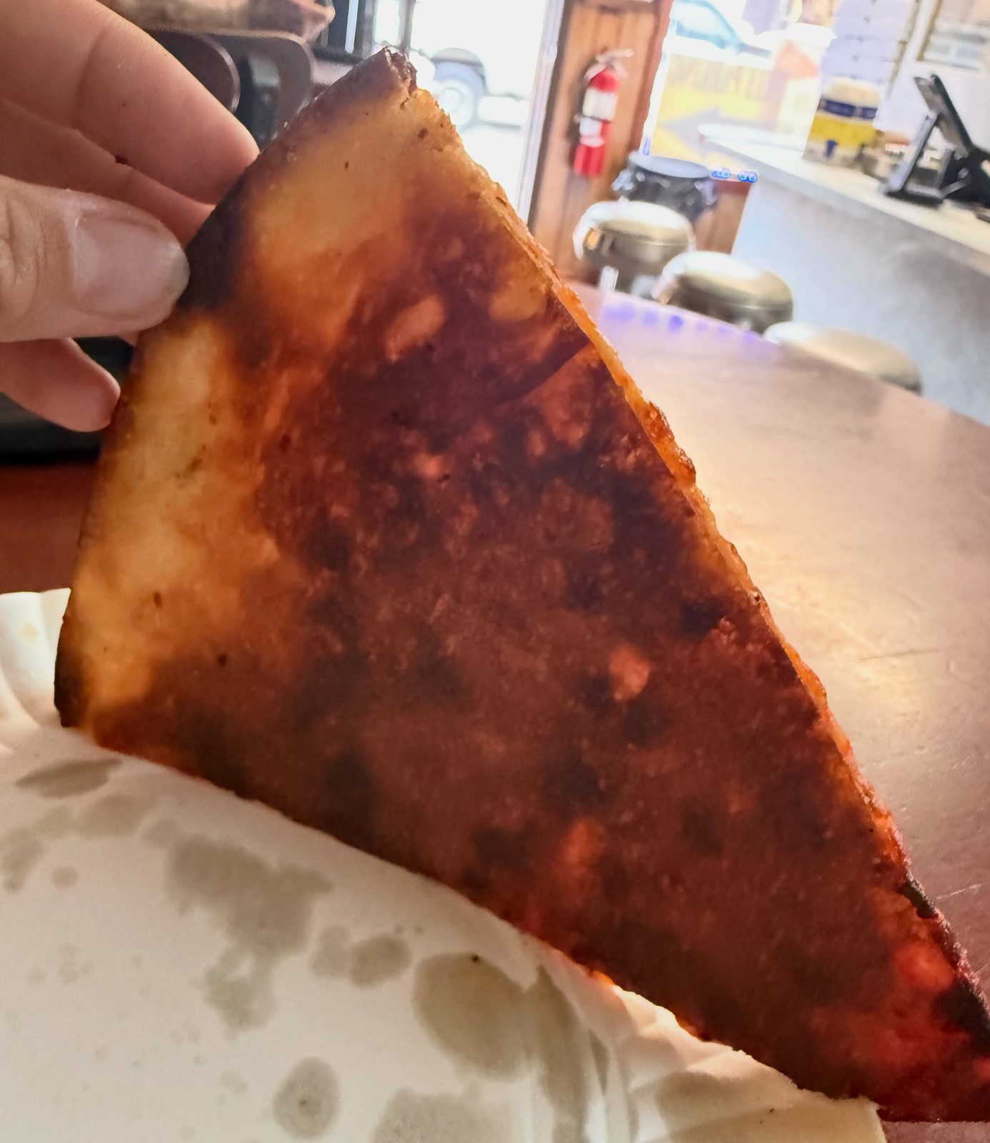 Underside of the Pizza Land slice, deeply browned and almost black at the rim