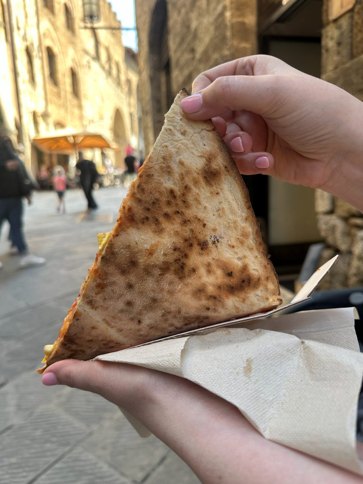 Underside of the slice showing a blistered, spotted base, Ricca Pizza