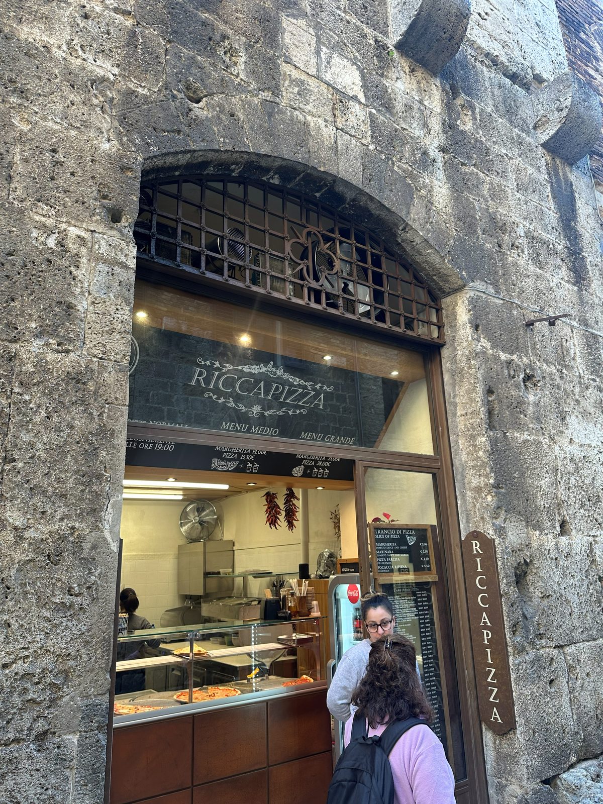 Riccapizza shopfront set into a stone archway, San Gimignano