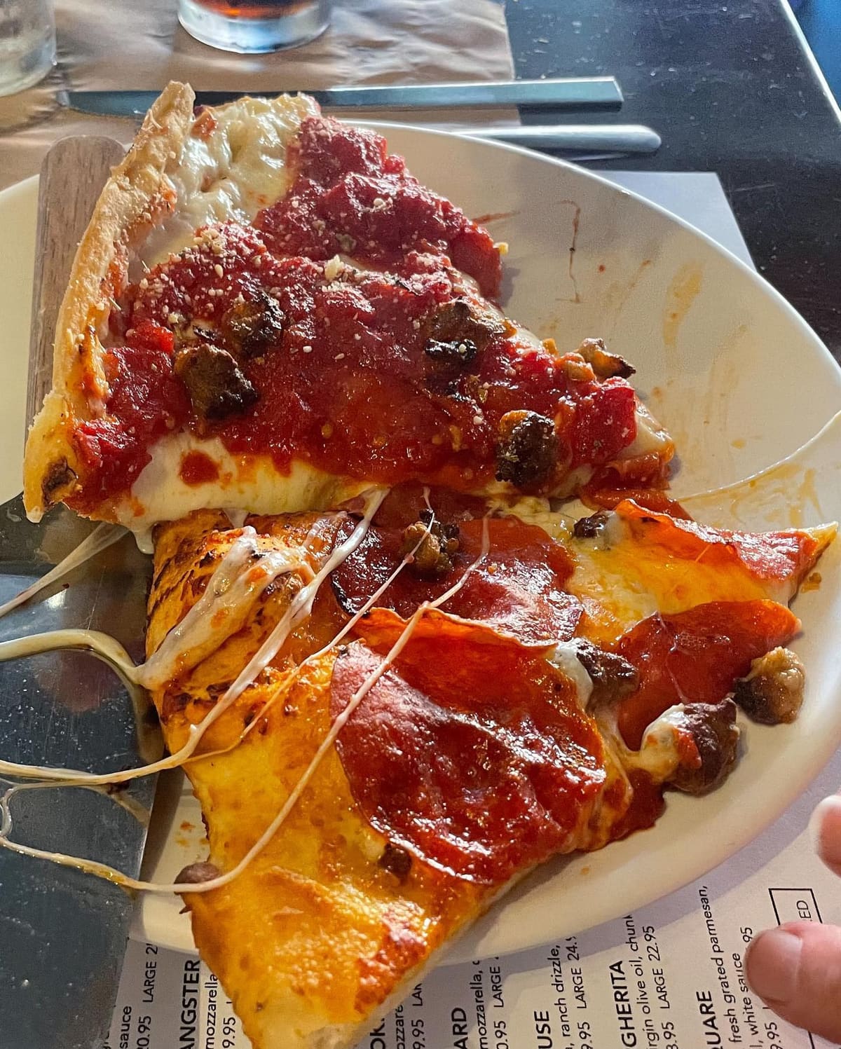 Pizza slice with melted cheese at Two Cities Pizza Co