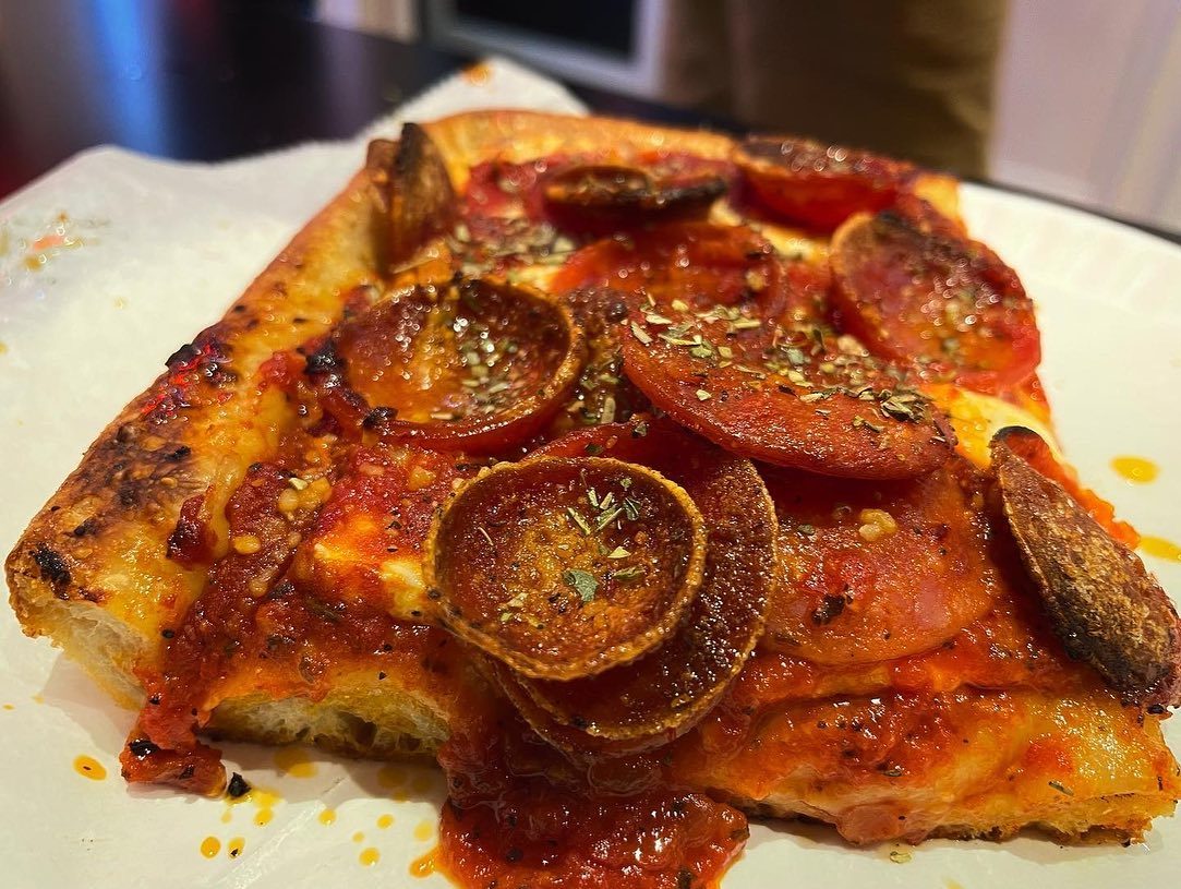 Close view of a pizza slice at Village Square Pizza