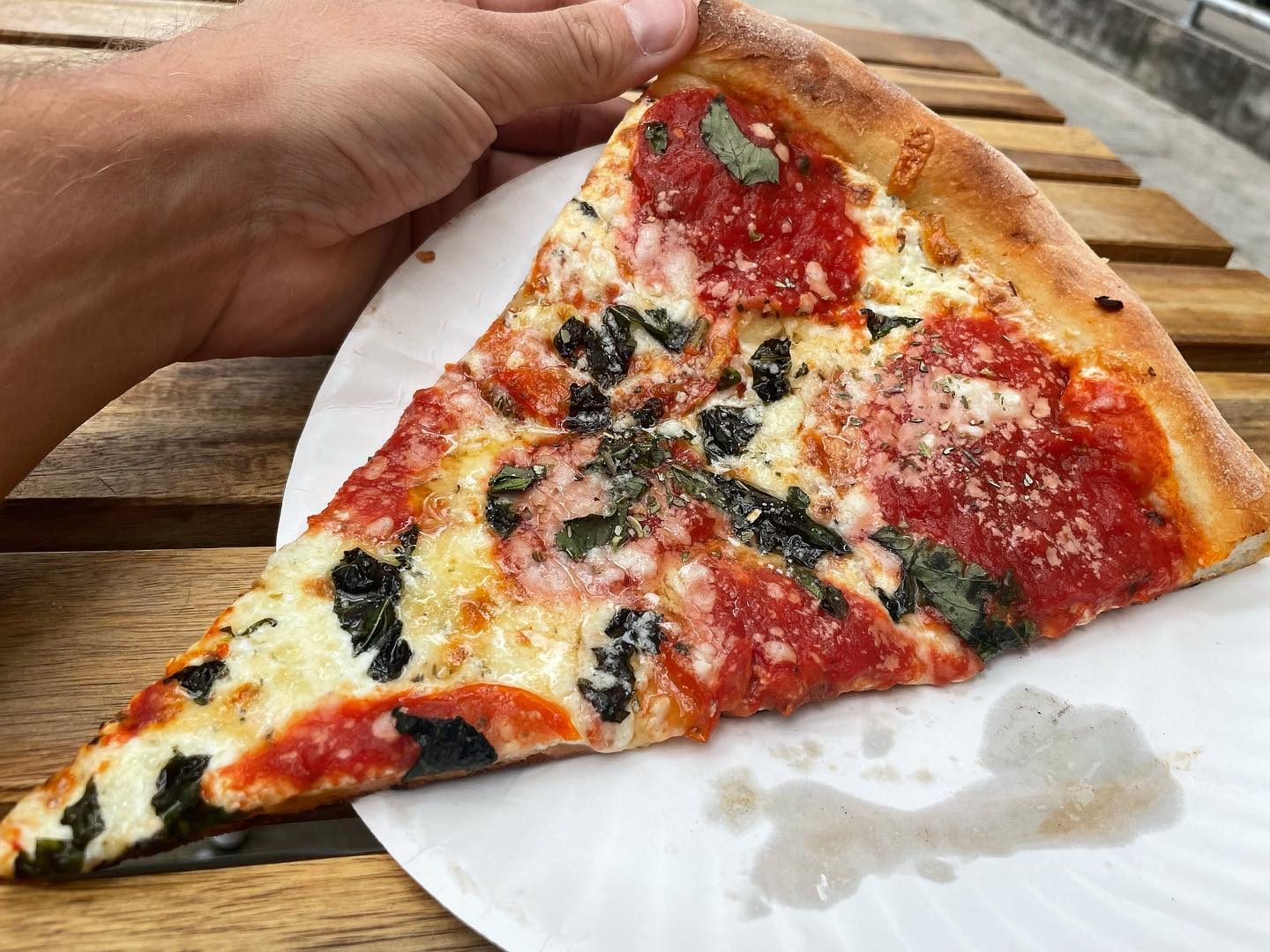 Pizza slice held up for a closer view at Vito’s Slices & Ices