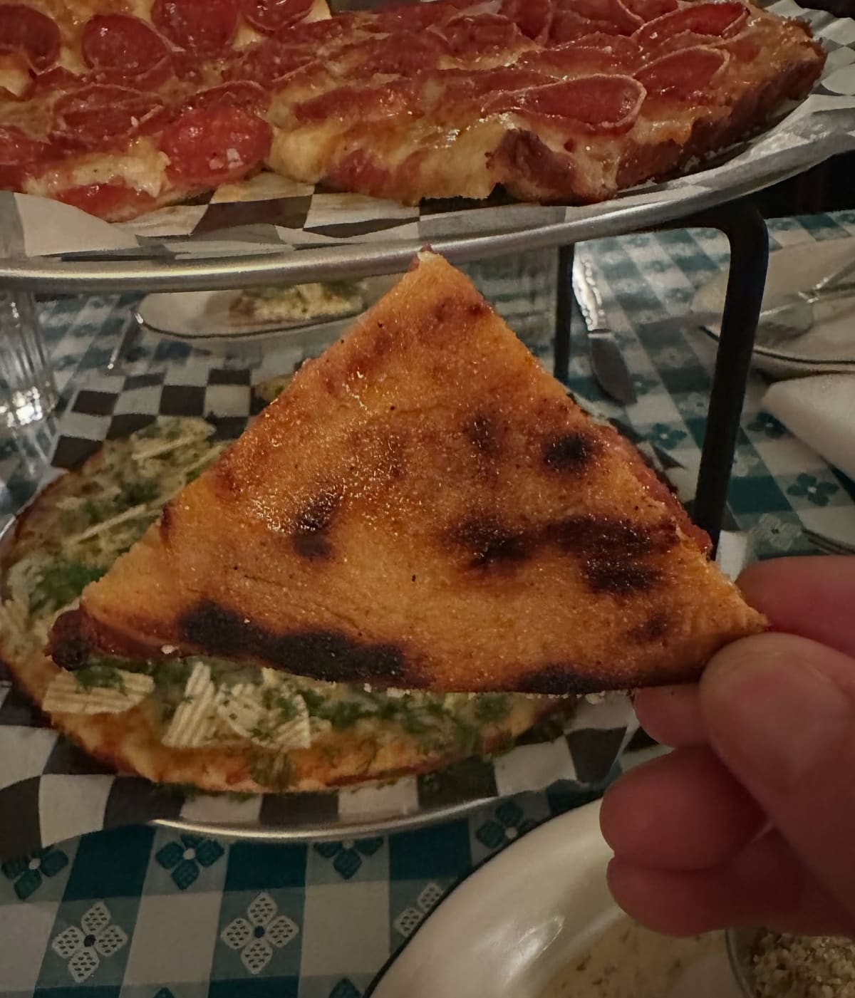 Pizza slice held up for a closer view at Wayfarer Tavern
