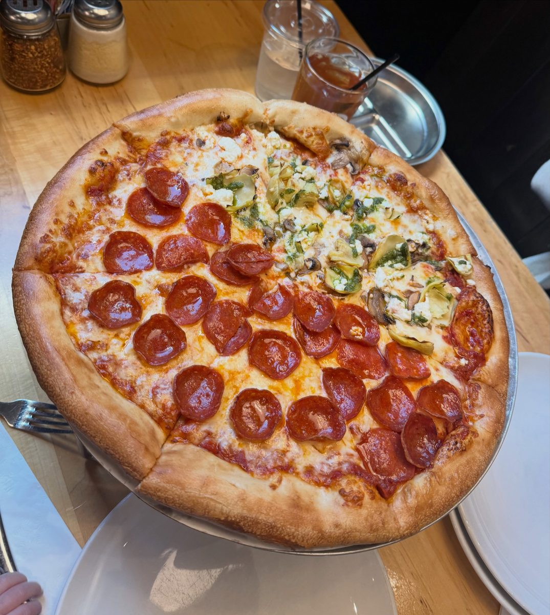 Whole Dewey's pie on a pan, half pepperoni and half artichoke, mushroom and feta, with a pale pillowy rim