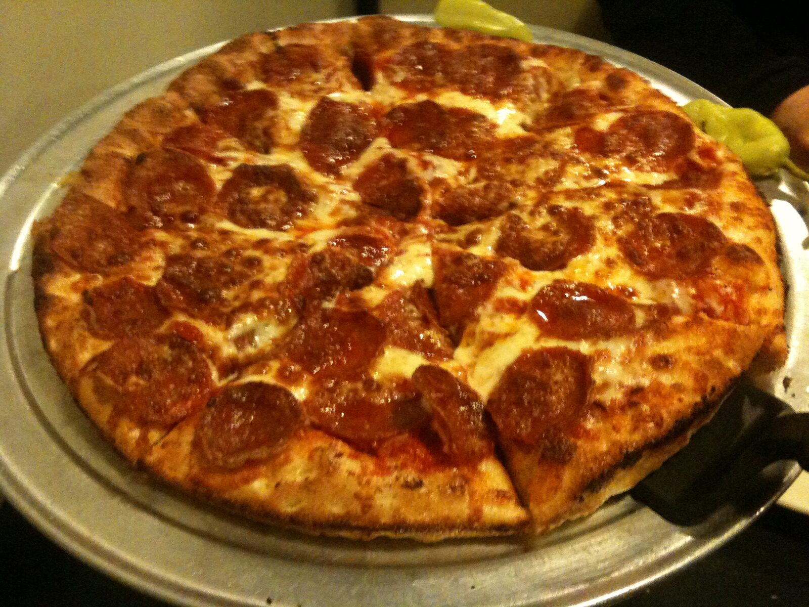 cup-and-curl pepperoni pie beside a bag of pepperoncini, Pepperoncini's Pizza