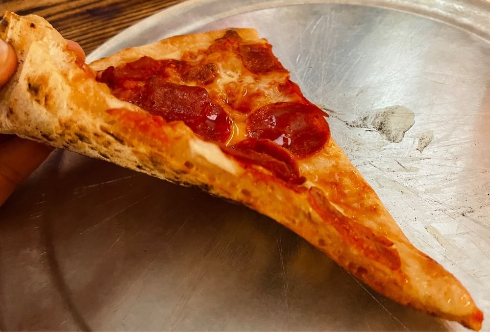blistered-crust pepperoni slice resting near the pan, Regina Pizza