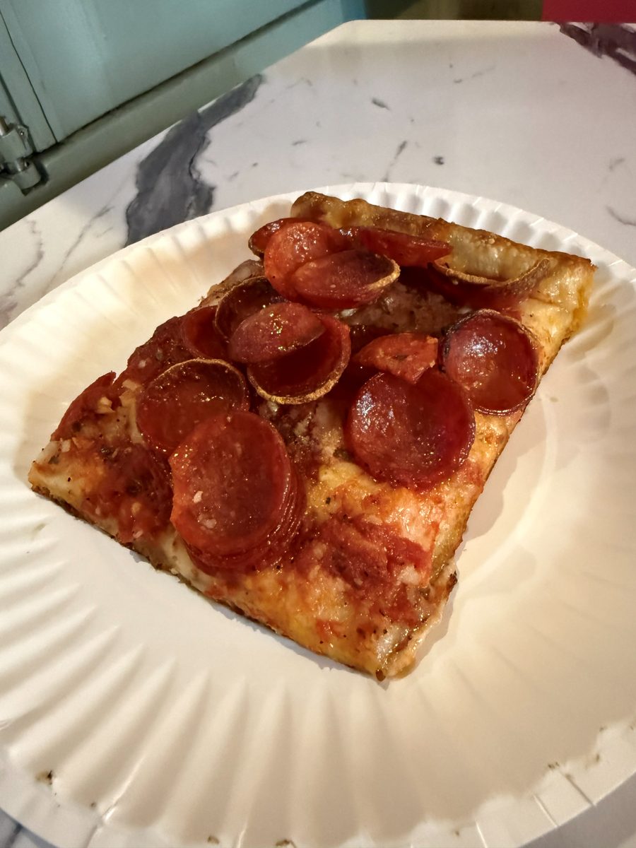 Square slice crowded with cupped pepperoni over a crisp browned edge, Rocco's Pizza