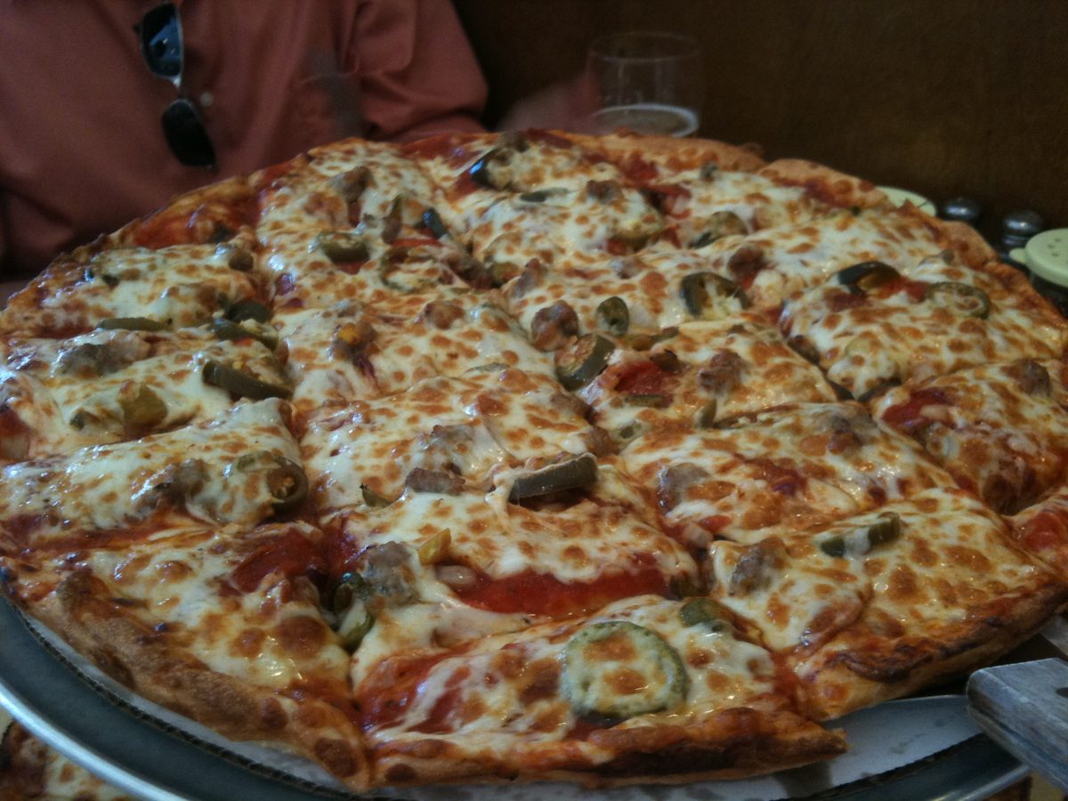 Wide pie topped with sausage crumbles and jalapeño rounds, Raymond's Pizza